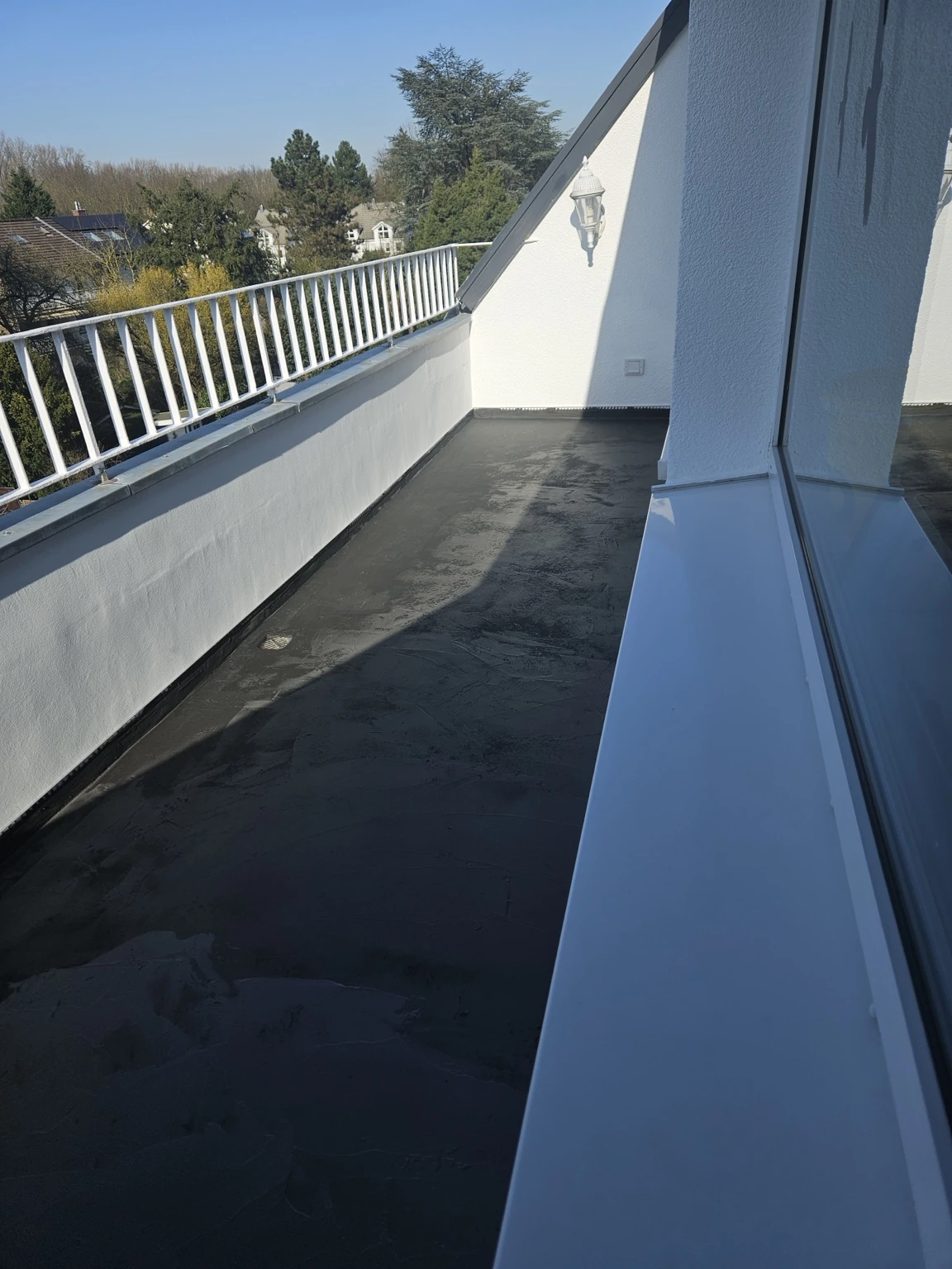 Langer Balkon mit vorbereitetem dunklem Untergrund vor dem Oberbelag