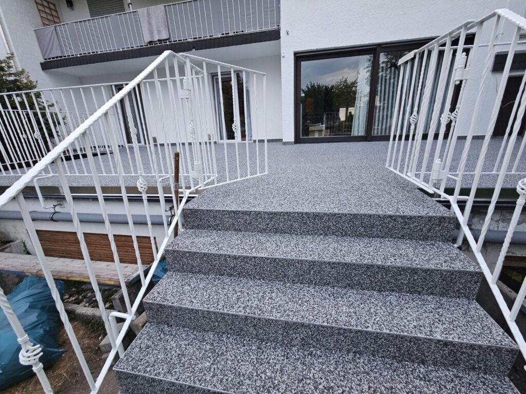Breite Außentreppe mit weißem Geländer nach der Oberflächenausführung
